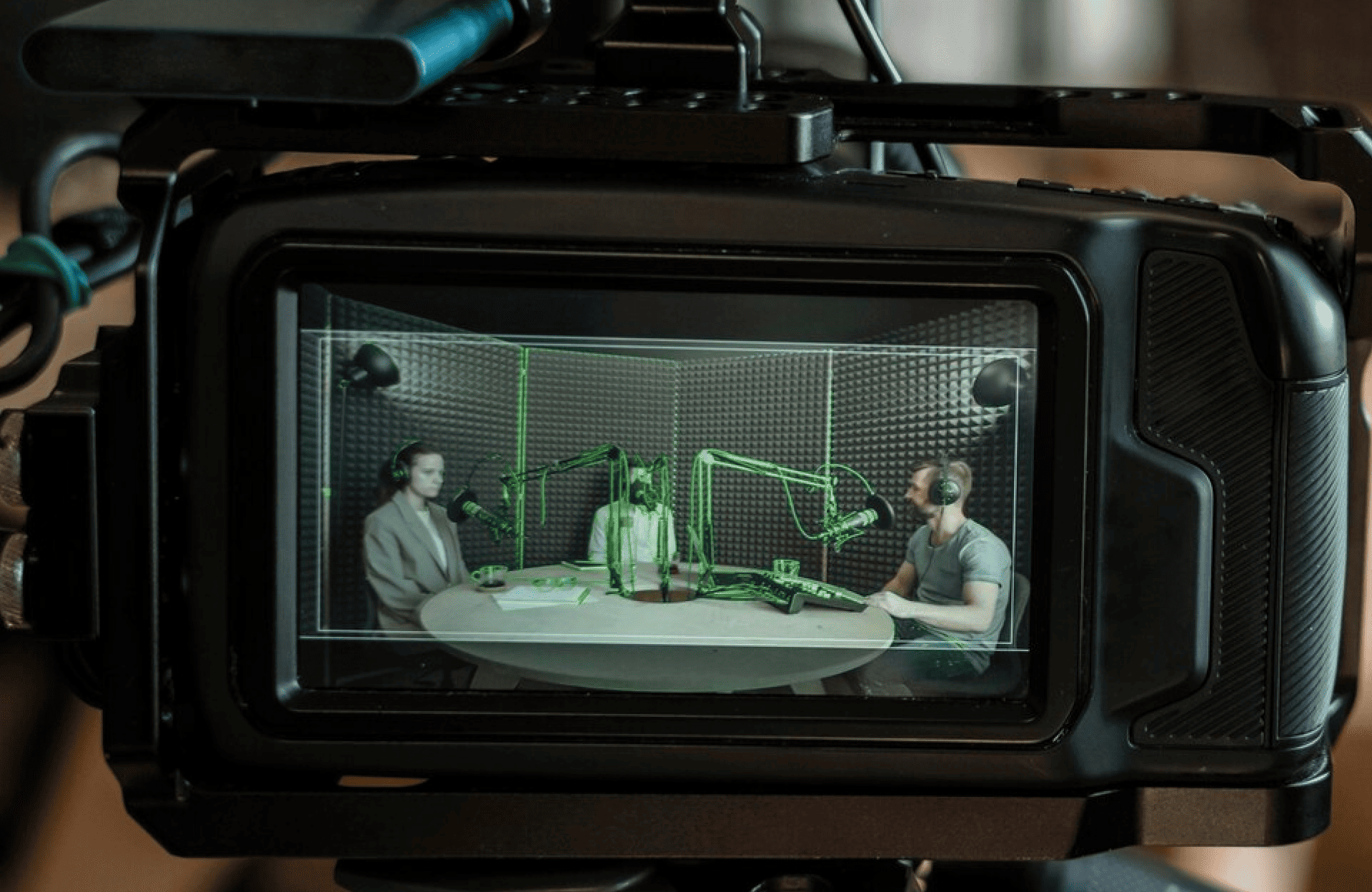 FX Productions Canada A camera screen displays three people with microphones sitting around a table in a soundproof studio, recording a podcast or radio show at Toronto Production Company. Toronto Video Production Company