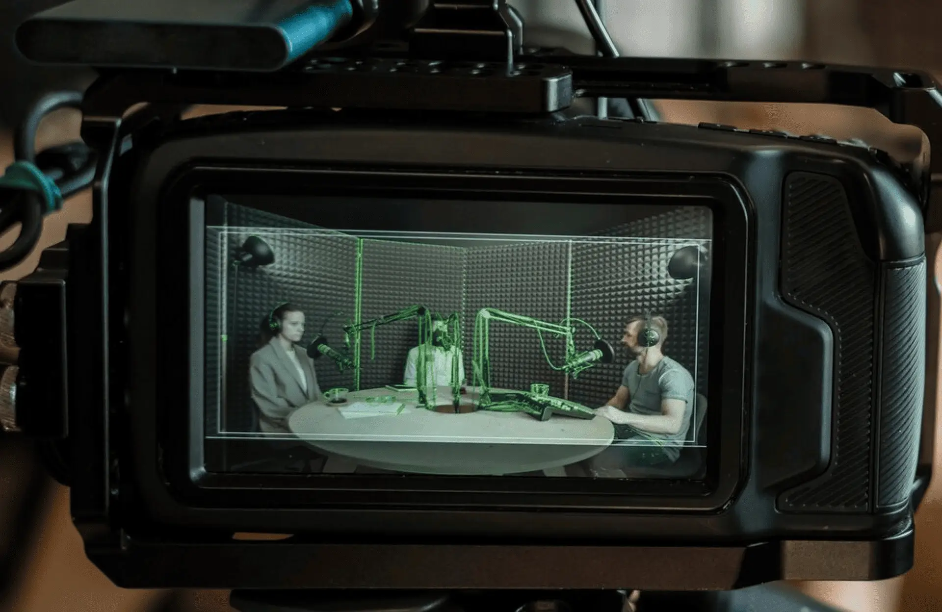 FX Productions Canada A camera screen displays three people with microphones sitting around a table in a soundproof studio, recording a podcast or radio show at Toronto Production Company. Toronto Video Production Company