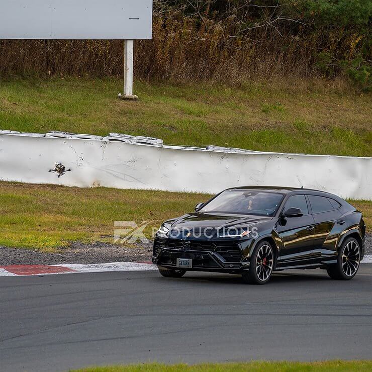 FX Productions Canada A black SUV driving on a race track near a curve, with a grassy area and a blank white sign in the background, captured by FX Productions Canada for a Toronto Video Production project. Toronto Video Production Company