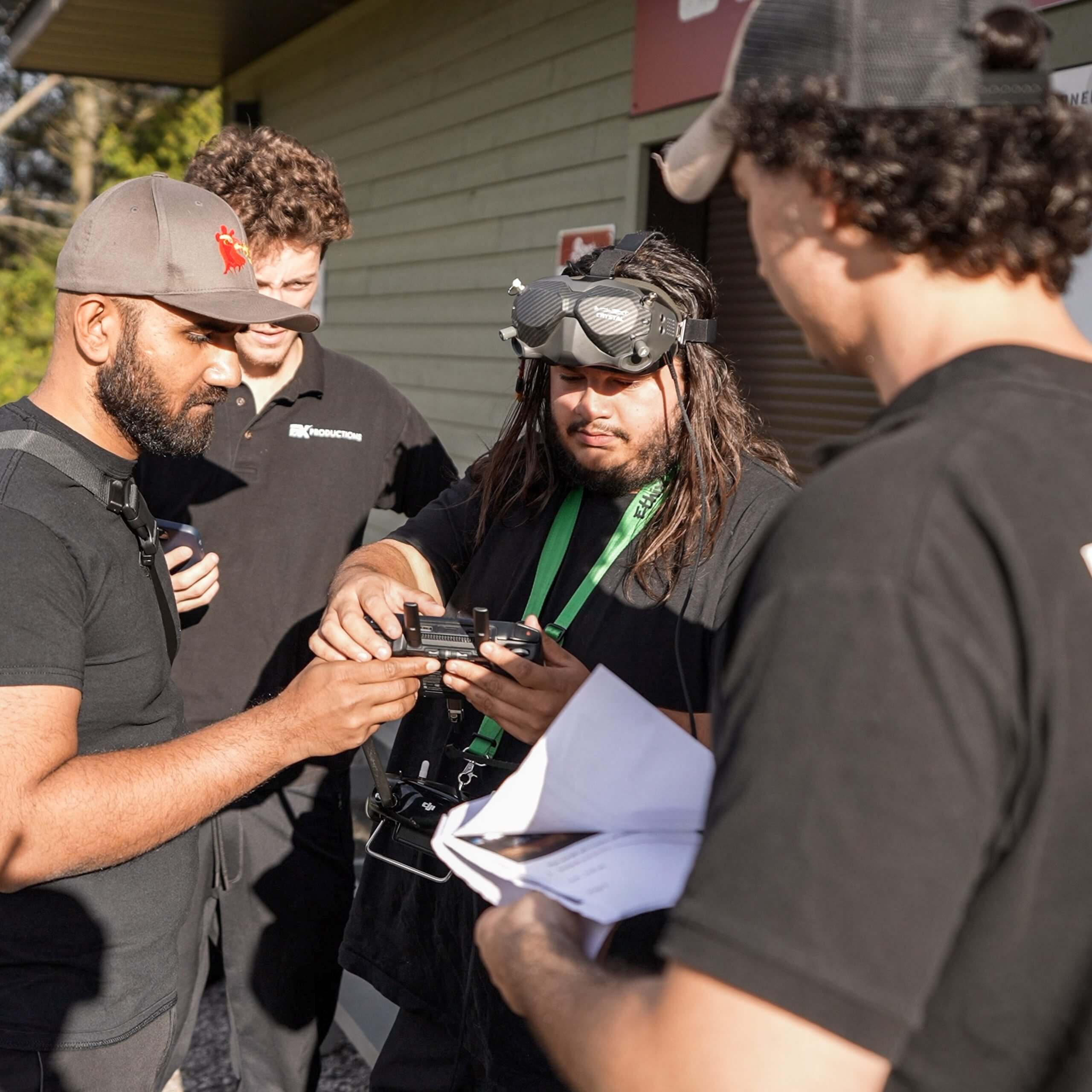 FX Productions Canada Four men stand outside a building, examining a device together; one holds papers, another wears goggles on his head—capturing teamwork at its best for FX Productions Canada, a leading Toronto Video Production company. Toronto Video Production Company