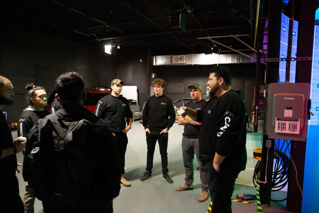 FX Productions Canada A group of people wearing black shirts stand in a studio, engaged in conversation beside technical equipment and cables at FX Productions Canada, a leading Toronto Video Production company. Toronto Video Production Company