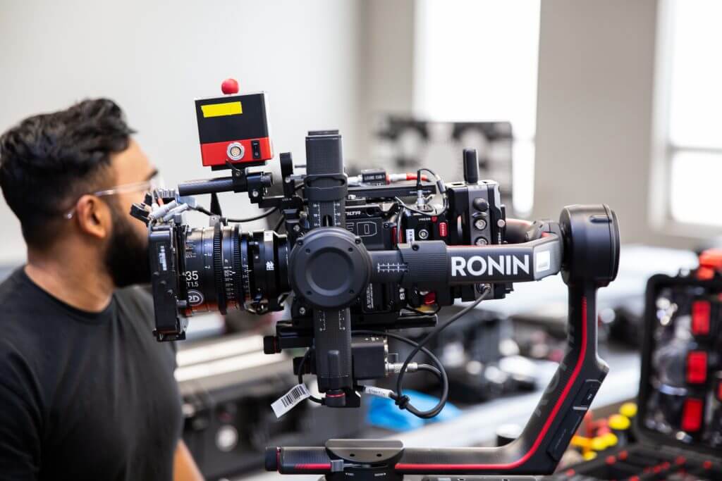 FX Productions Canada A person stands next to a professional camera setup with a Ronin stabilizer in a well-lit indoor environment, reflecting the expertise of a leading Toronto Video Production company. Toronto Video Production Company