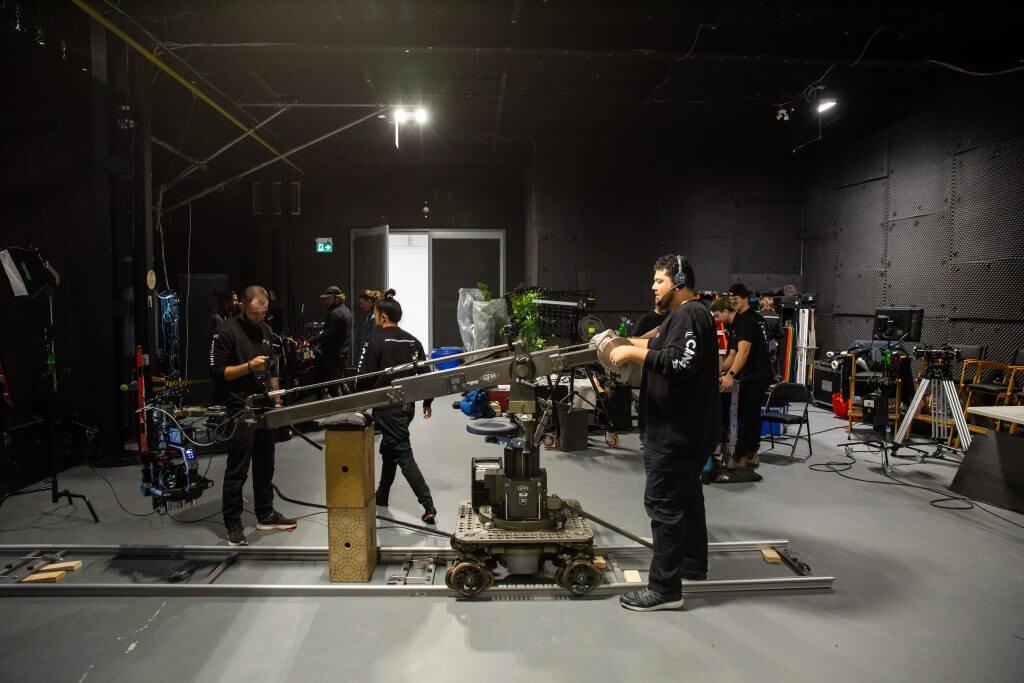 FX Productions Canada Film crew from a Toronto Video Production company operating camera equipment on a dolly and crane inside a studio, with various lighting and filming gear visible. Toronto Video Production Company