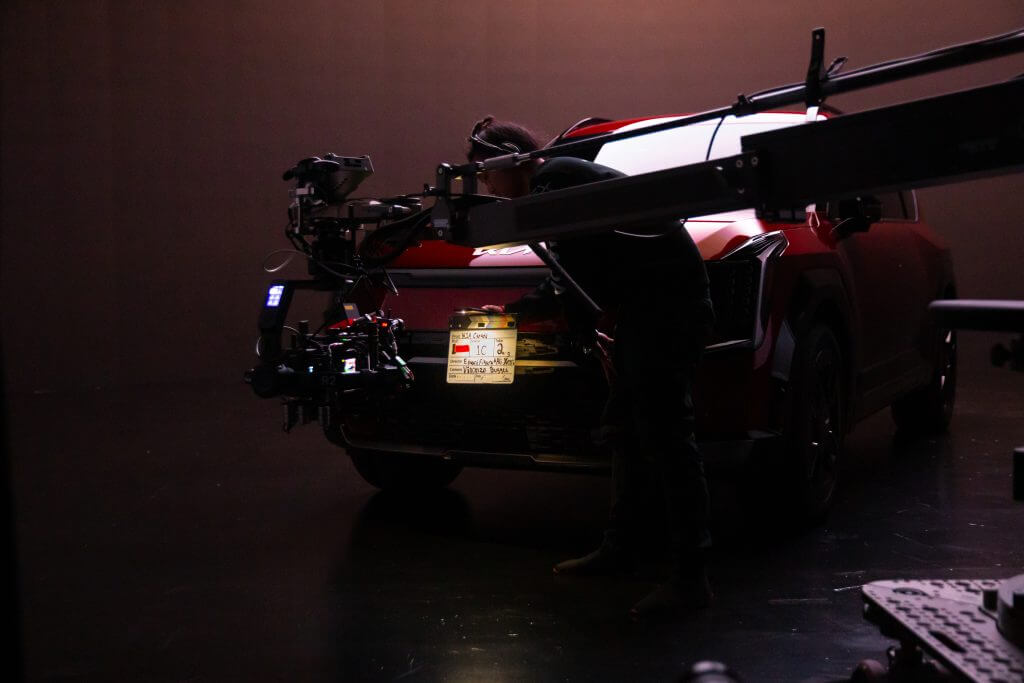 FX Productions Canada A person operates a camera rig filming the rear of a red SUV in a studio with controlled lighting, showcasing the expertise of FX Productions Canada, a leading video production company. Toronto Video Production Company