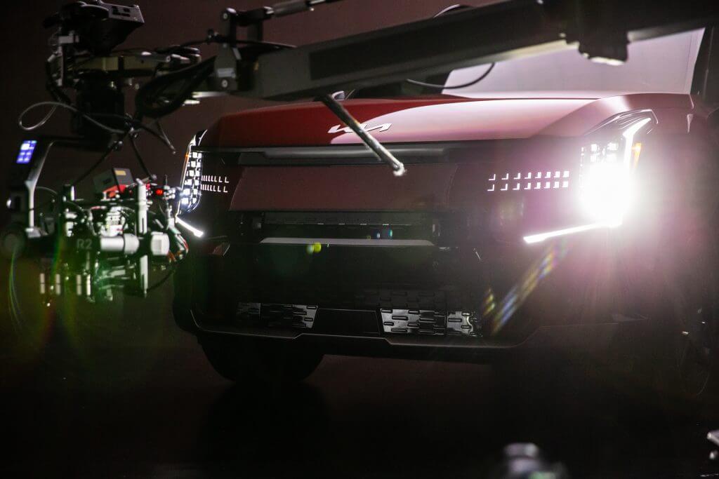 FX Productions Canada A close-up of the front of a red Kia vehicle with headlights on, surrounded by professional film cameras and equipment in a Toronto Video Production studio setting. Toronto Video Production Company