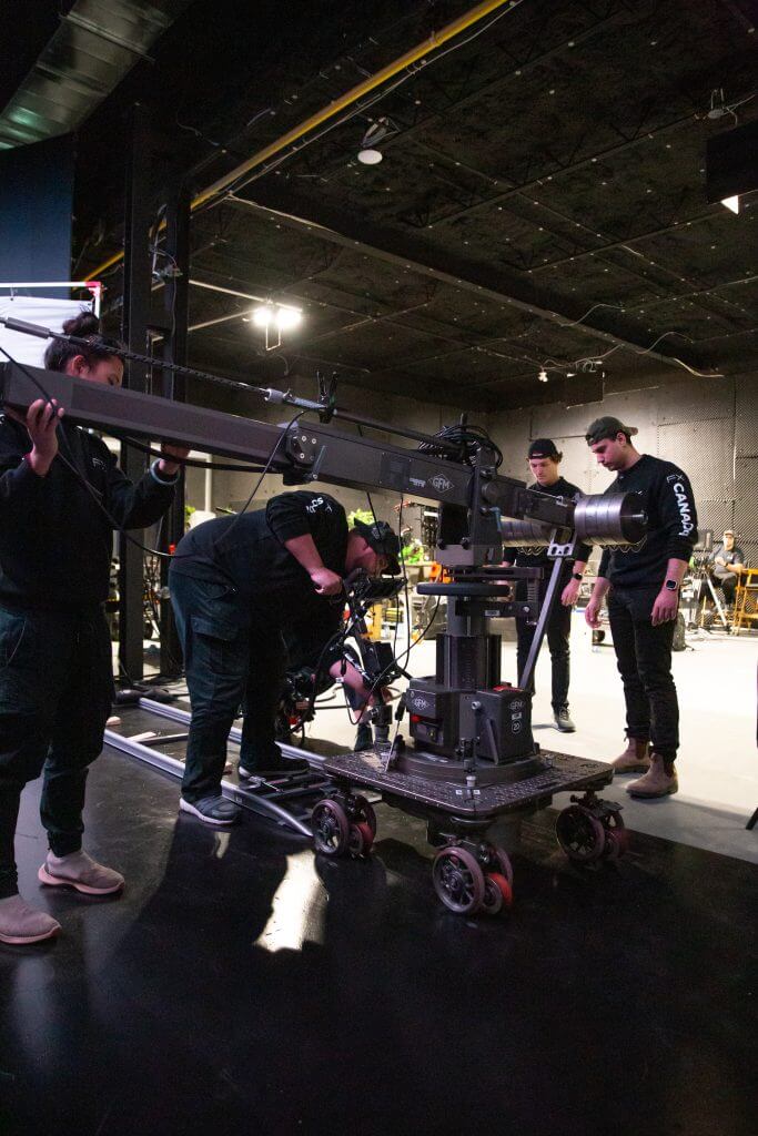 FX Productions Canada A film crew with FX Productions Canada operates a camera mounted on a dolly and crane inside a studio, adjusting equipment while preparing for a Toronto Video Production shoot. Toronto Video Production Company