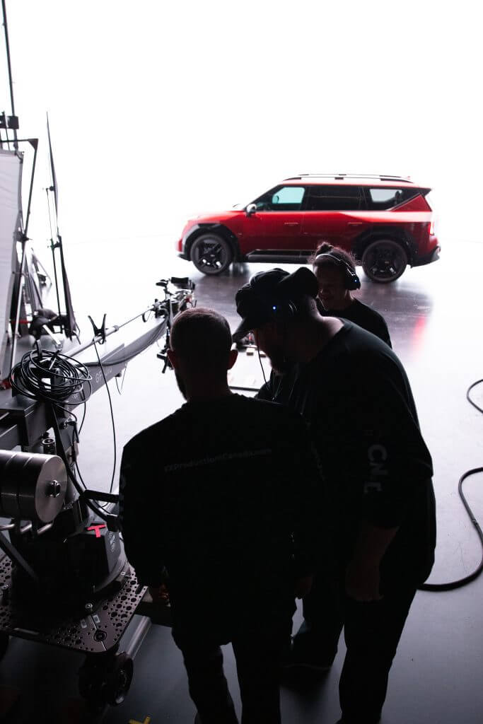 FX Productions Canada Three crew members operate film equipment in a studio, with a red SUV under bright lights in the background—a typical scene at FX Productions Canada, a leading Toronto Video Production company. Toronto Video Production Company