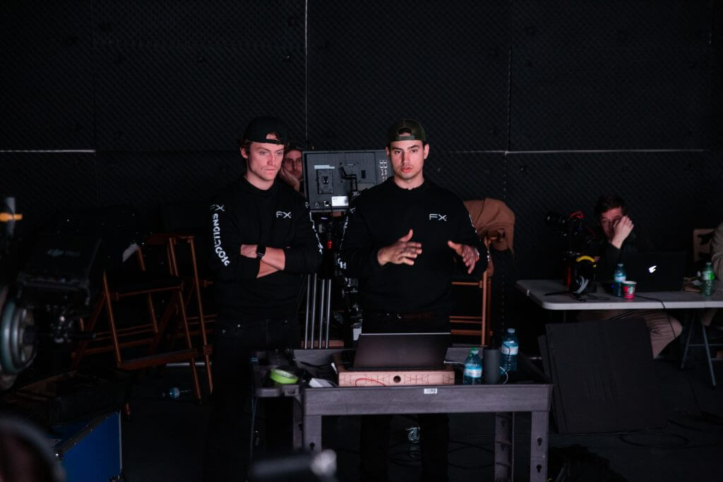FX Productions Canada Two men in black shirts stand by camera equipment in a dimly lit studio at FX Productions Canada, while others sit at a table with laptops and drinks in the background. Toronto Video Production Company