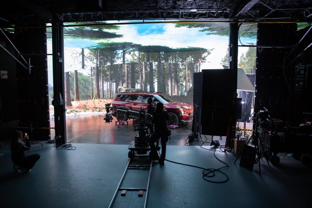 FX Productions Canada Crew members at FX Productions Canada film a car in front of a large LED screen displaying a forest scene, with various camera and lighting equipment visible in the Toronto video production studio. Toronto Video Production Company