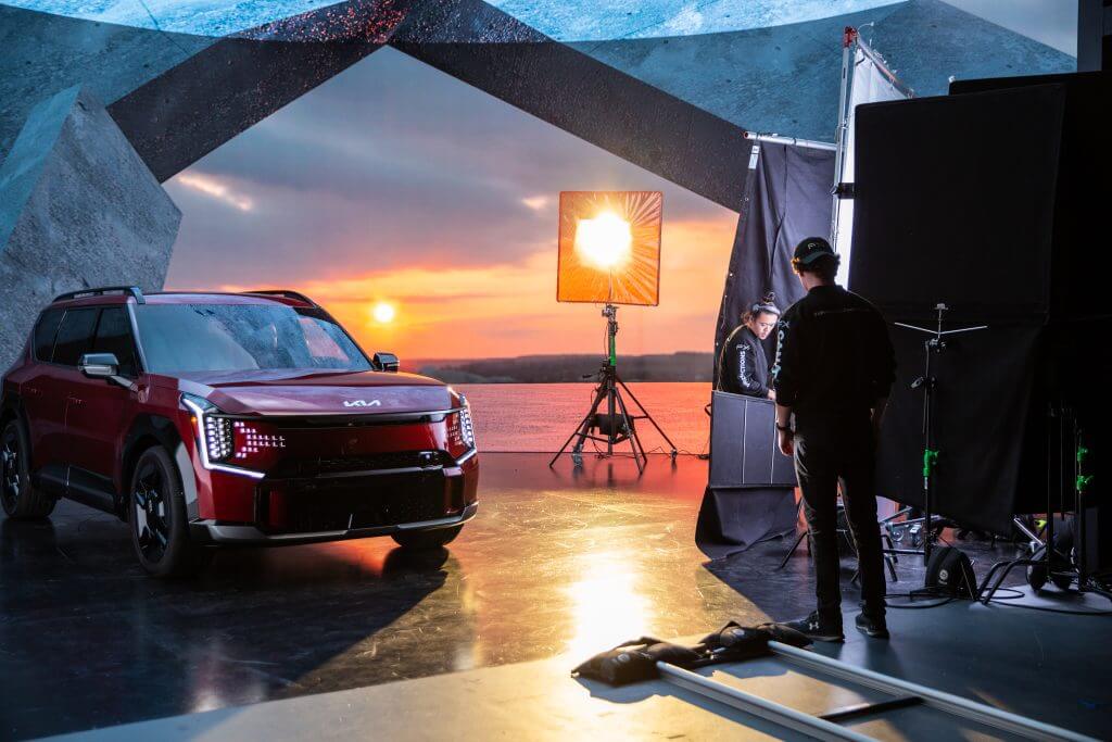 FX Productions Canada A red Kia SUV is positioned indoors near photography equipment as a sunset backdrop and lighting setup are visible, with two people from FX Productions Canada working on the scene. Toronto Video Production Company