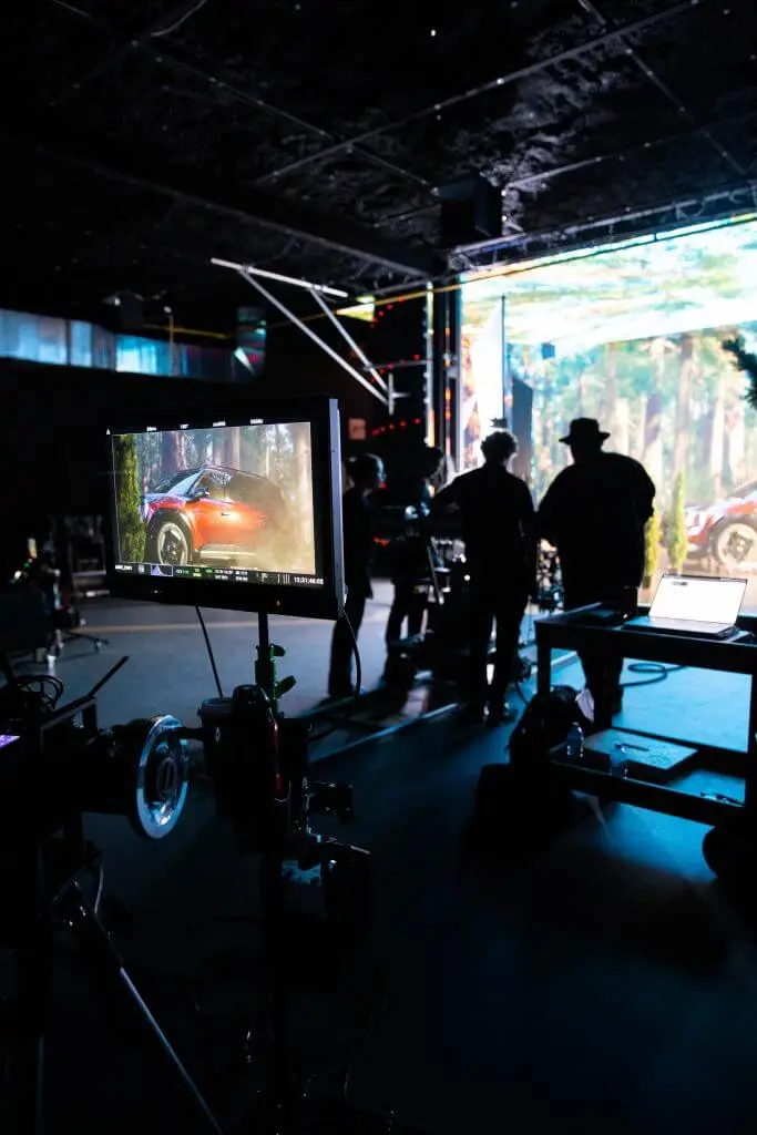 FX Productions Canada A film production set with crew silhouettes, equipment, and a monitor displaying a car scene, with a forest backdrop—capturing the expertise of FX Productions Canada. Toronto Video Production Company