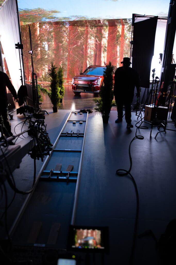 FX Productions Canada A studio setup by Toronto Video Production features camera tracks and filming equipment aimed at a car parked before a forest backdrop, with crew members from the video production company standing nearby. Toronto Video Production Company