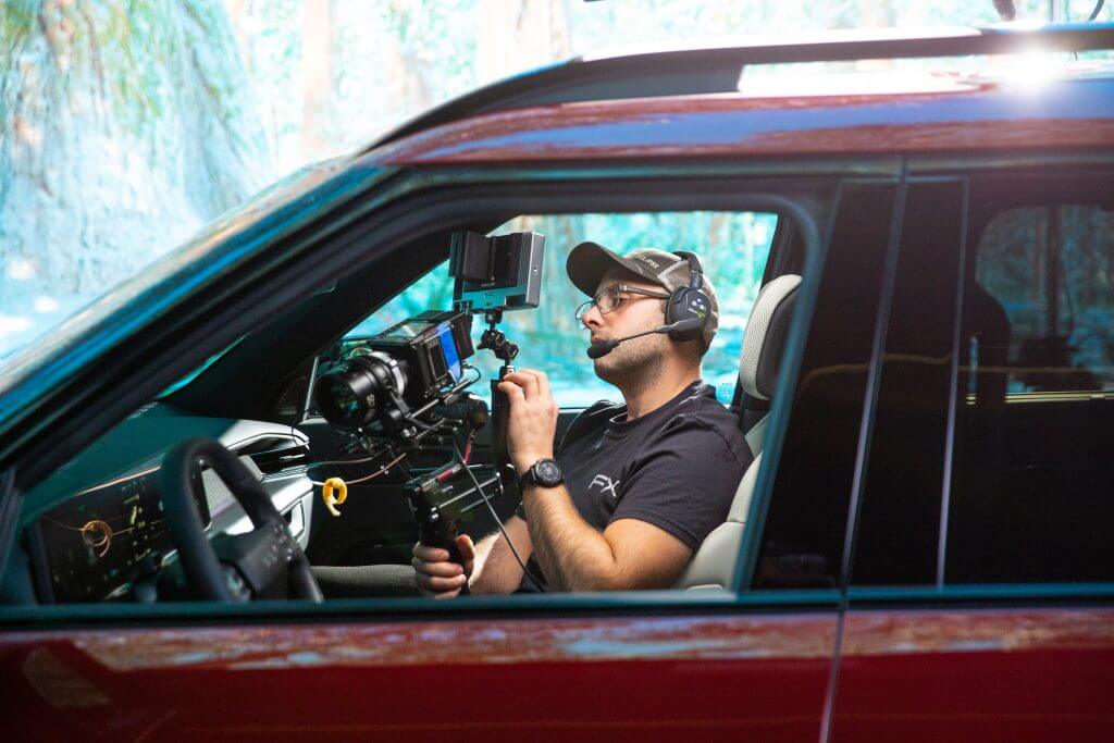 FX Productions Canada A person wearing a headset operates a camera rig inside the driver's seat of a red vehicle for FX Productions Canada. Toronto Video Production Company