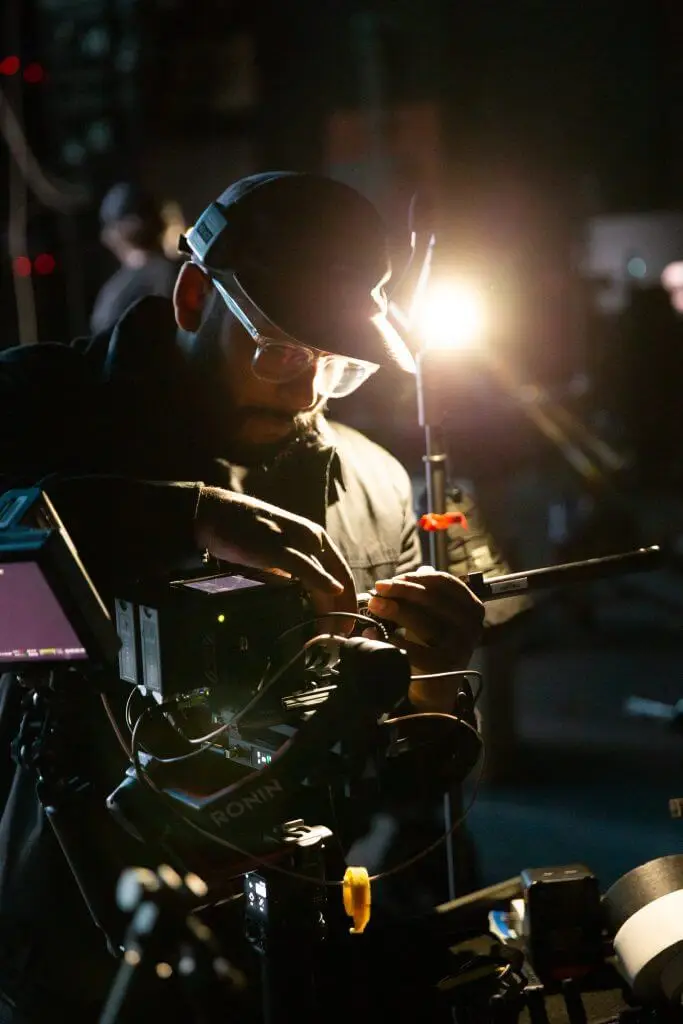 FX Productions Canada Person adjusting professional video camera equipment on a set, wearing headphones and a cap, with bright studio light in the background—capturing the essence of a Toronto Video Production by FX Productions Canada. Toronto Video Production Company