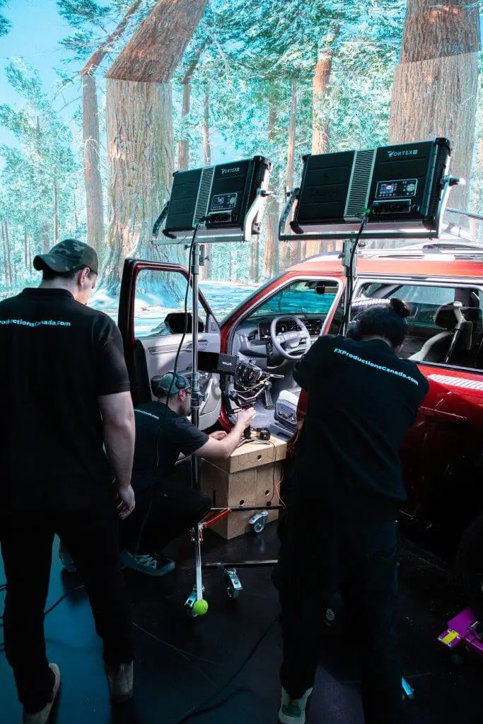 FX Productions Canada Three people adjust equipment inside a car under studio lights, with a forest scene displayed on the surrounding screens—a glimpse behind the scenes at FX Productions Canada, a leading Toronto Video Production company. Toronto Video Production Company