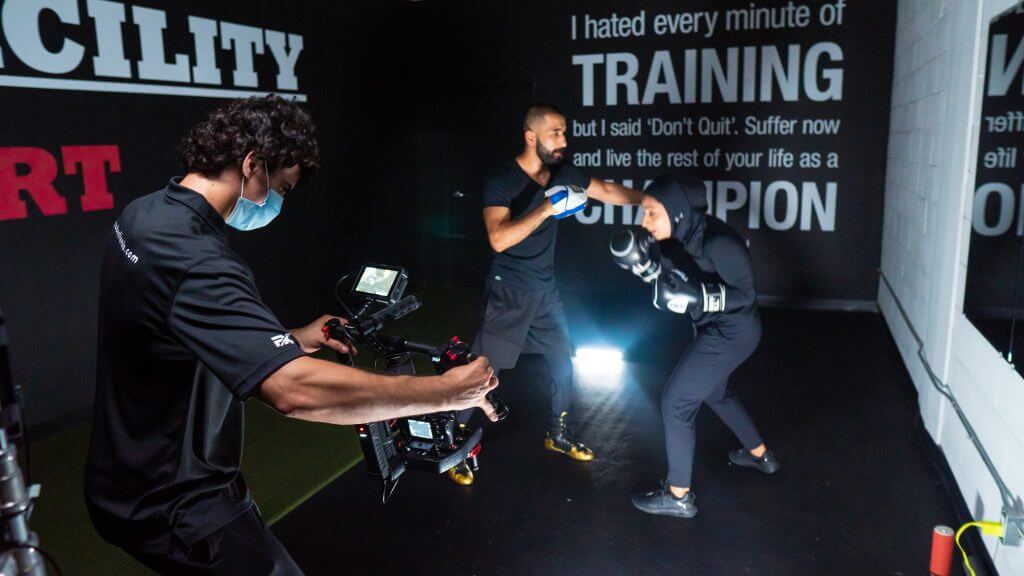 FX Productions Canada A cameraman from FX Productions Canada films two people sparring in a gym, while motivational quotes are displayed on the wall in the background. Toronto Video Production Company