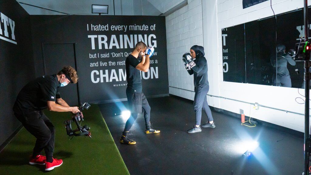 FX Productions Canada Two people practice boxing in a gym while a cameraman from FX Productions Canada films them; a motivational quote by Muhammad Ali is displayed on the wall behind them. Toronto Video Production Company