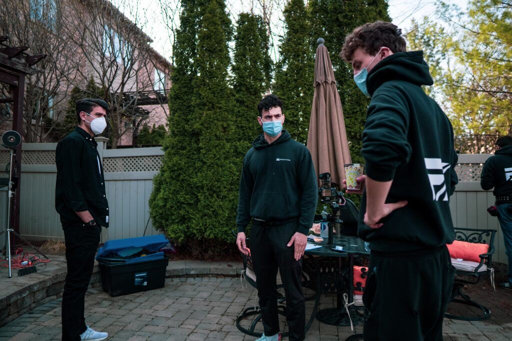 FX Productions Canada Three young men wearing masks stand outdoors in a backyard patio area, surrounded by trees, patio furniture, and equipment—capturing a behind-the-scenes moment with FX Productions Canada, a leading Toronto Video Production team. Toronto Video Production Company