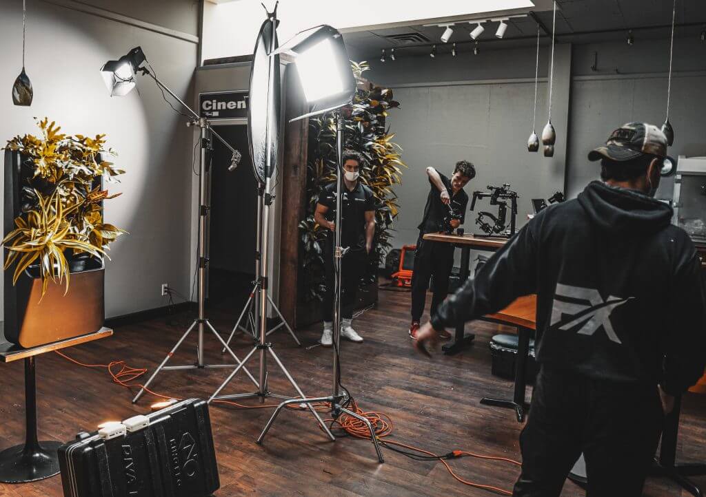 FX Productions Canada A film crew from FX Productions Canada sets up lighting and camera equipment in an indoor studio with wooden floors and potted plants. Three people are adjusting gear. Toronto Video Production Company