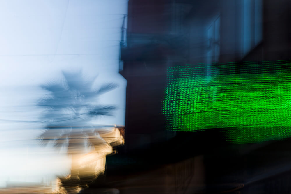 FX Productions Canada Abstract blurred image featuring a palm tree on the left, a building, and a green digital display on the right, with streaks of motion—capturing the dynamic creativity of Toronto Video Production. Toronto Video Production Company