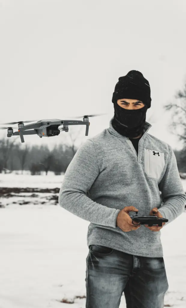 A fully licensed drone pilot in a black mask preparing a drone for aerial services