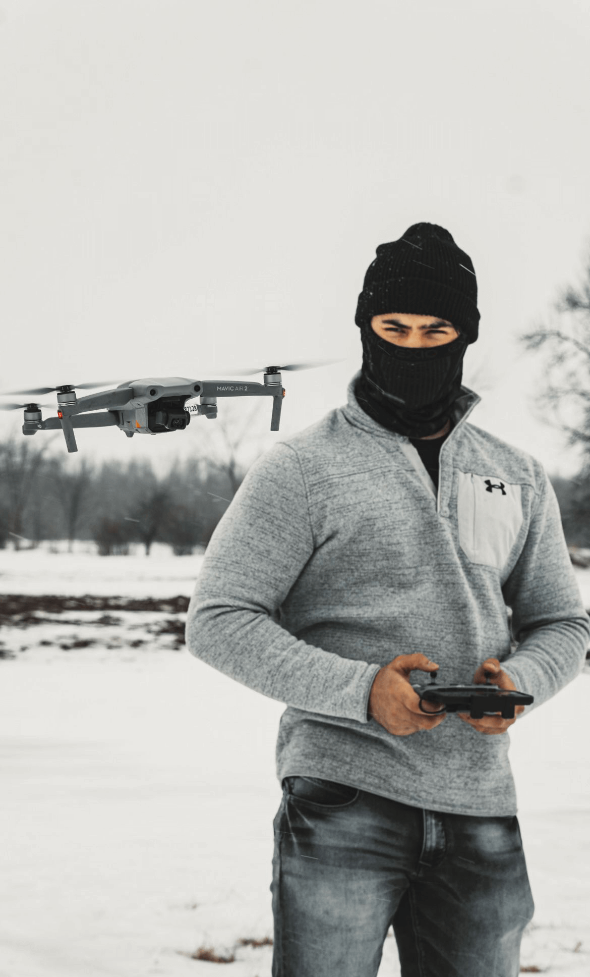 A fully licensed drone pilot in a black mask preparing a drone for aerial services
