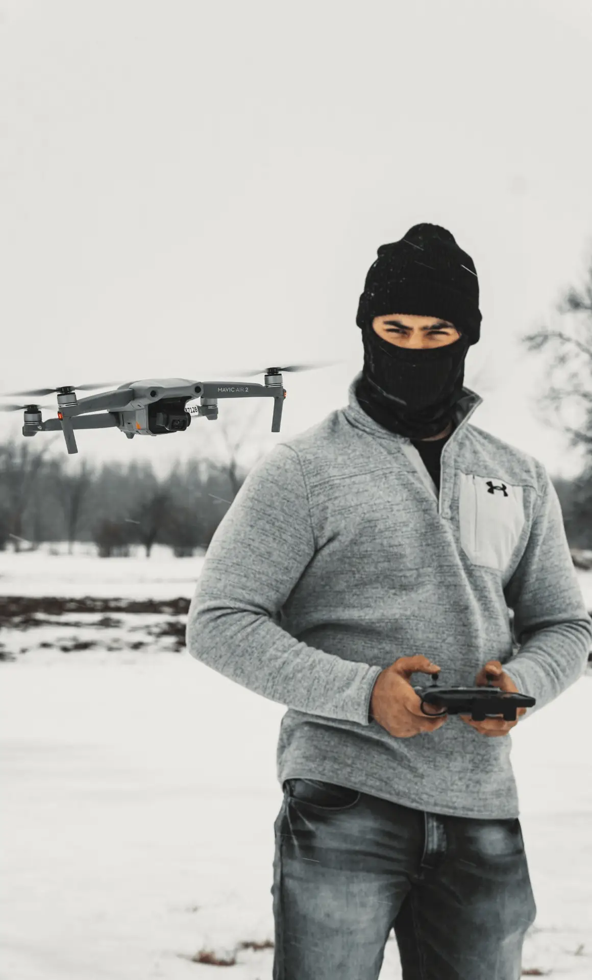 A fully licensed drone pilot in a black mask preparing a drone for aerial services