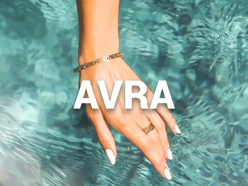 AVRA in text with the background of hand with ring and a bracelet and water