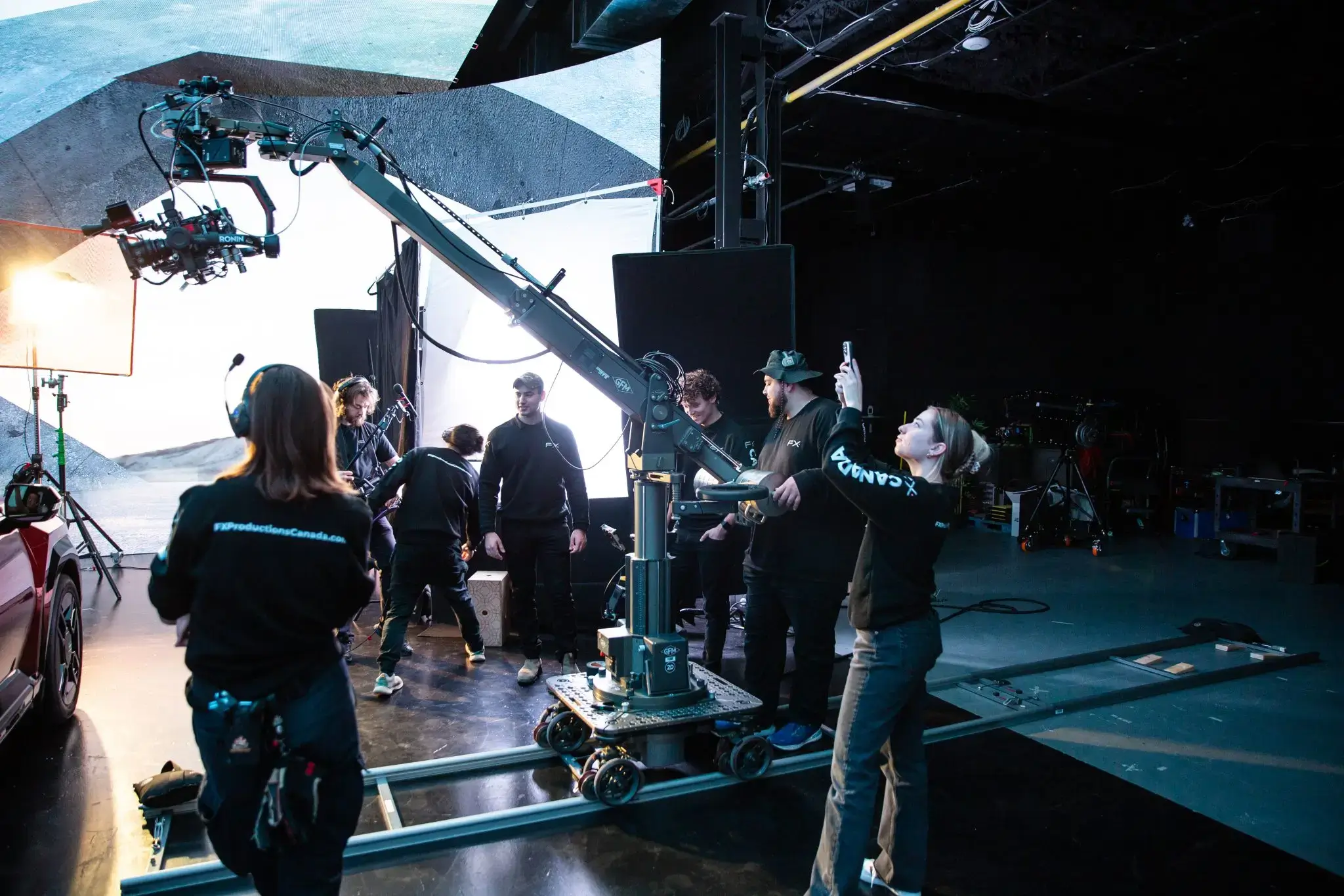 People gathered around a vehicle in a studio environment.
