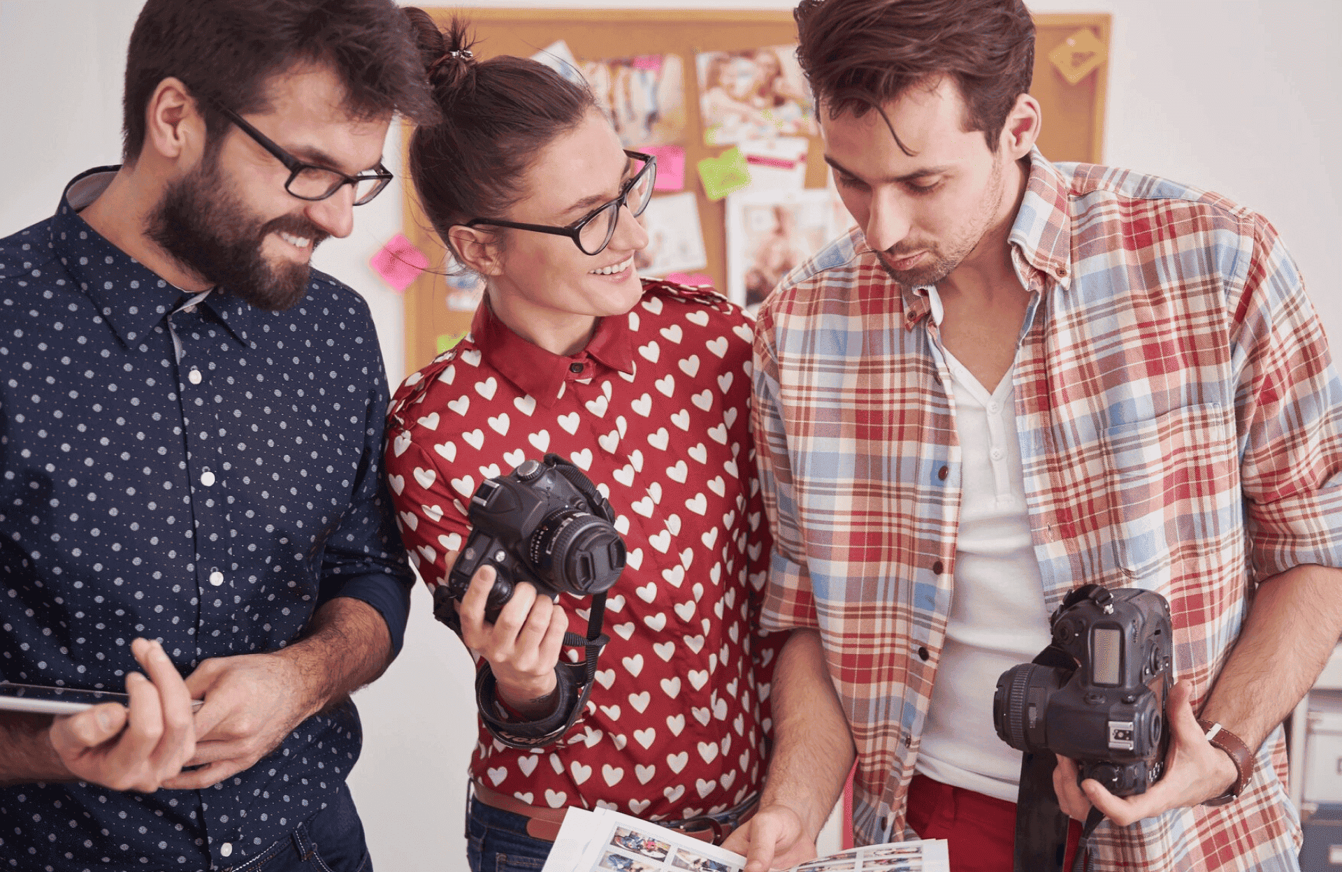 FX Productions Canada Three people stand together in an office, holding cameras and looking at printed photos, with a corkboard visible in the background—a glimpse behind the scenes at Toronto Production Company. Toronto Video Production Company