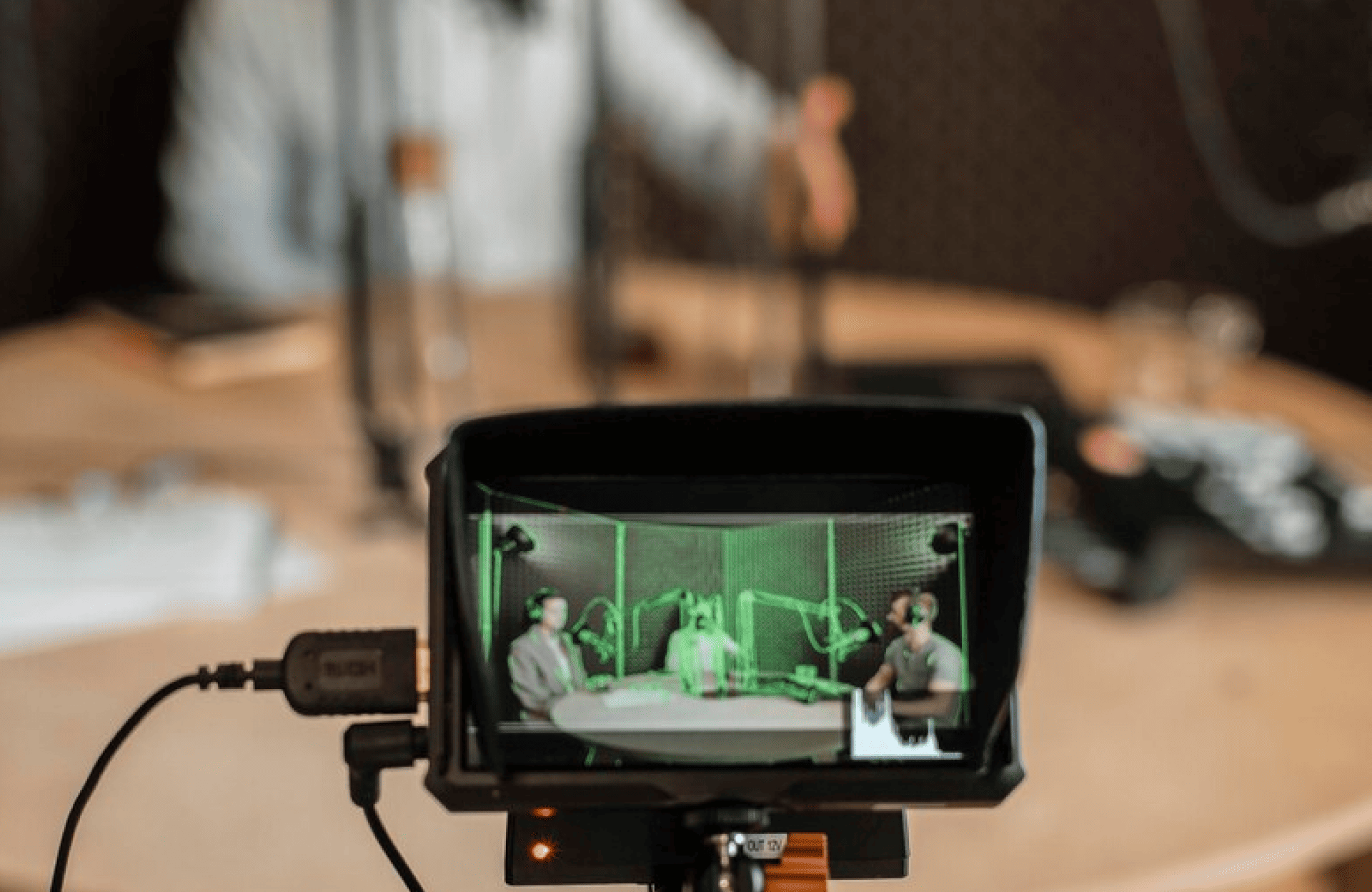 FX Productions Canada A camera display shows three people wearing headphones and speaking into microphones while recording a podcast at a round table, produced by Toronto Production Company. Toronto Video Production Company