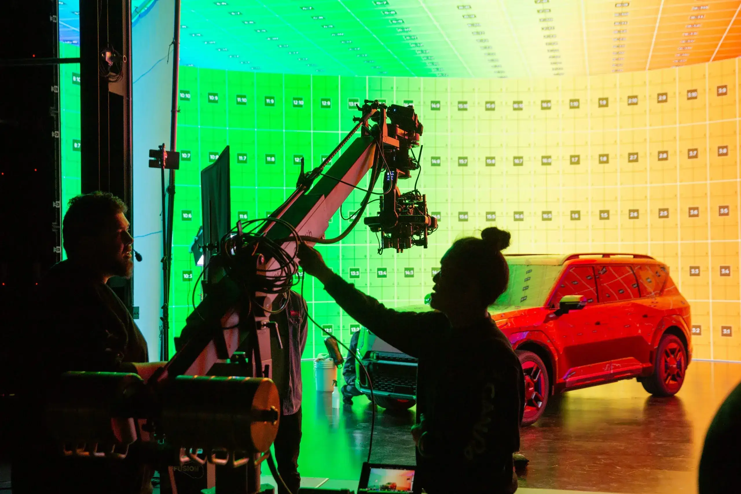 FX Productions Canada A Toronto Video Production crew operates a camera rig in a studio, where FX Productions Canada creates stunning visuals with a large LED screen showing a green-to-yellow gradient and a red SUV parked in the background. Toronto Video Production Company
