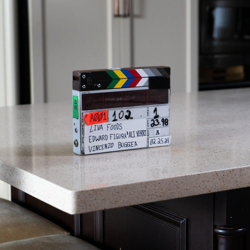 FX Productions Canada A film clapperboard labeled "LIVA FOODS" rests on a kitchen counter, displaying production details and dated 02.25.24, showcasing the work of a leading Toronto Video Production company. Toronto Video Production Company