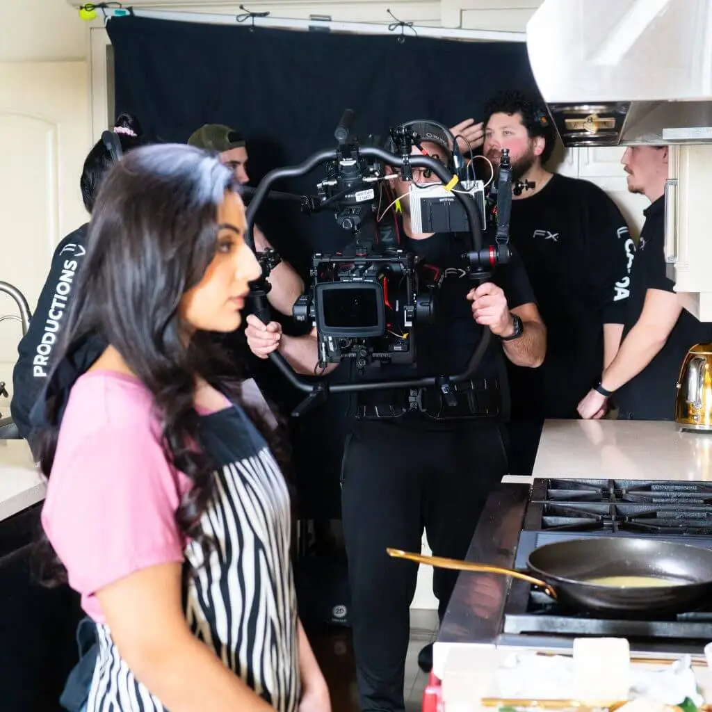 FX Productions Canada A film crew from FX Productions Canada records a woman in an apron standing by a stove in a kitchen, with cameras and equipment visible in the background. Toronto Video Production Company