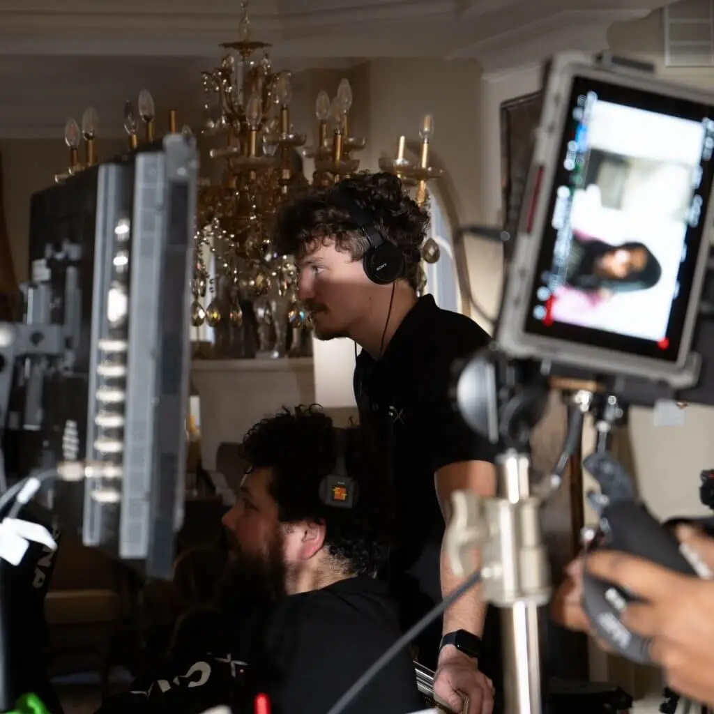 FX Productions Canada Two people wearing headsets monitor screens and filming equipment on a set for FX Productions Canada, with a chandelier and ornate decor in the background—a glimpse into professional Toronto Video Production. Toronto Video Production Company