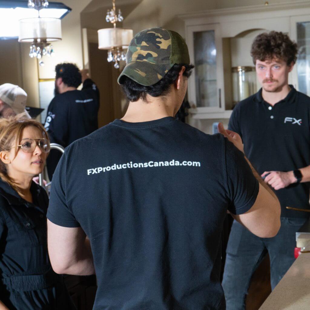 FX Productions Canada Three people stand and converse in a well-lit room, two wearing "FXProductionsCanada.com" shirts; filming equipment is visible in the background, highlighting this Toronto Video Production team's professionalism. Toronto Video Production Company