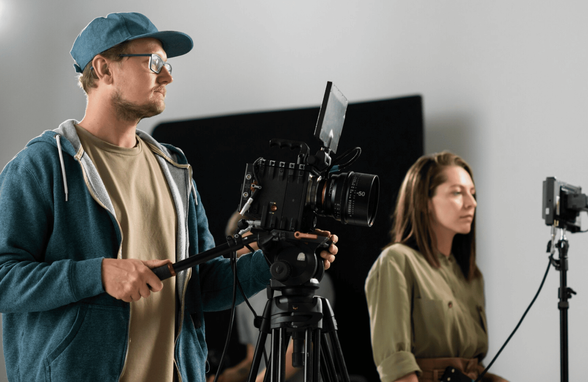 FX Productions Canada A man operates a professional video camera on a tripod while a woman stands nearby in a studio setting with lighting equipment, showcasing the expertise of Toronto Production Company FX Productions Canada. Toronto Video Production Company