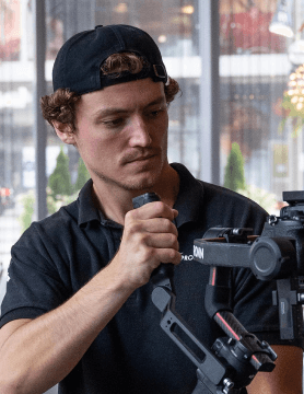 FX Productions Canada A man wearing a black cap and black shirt operates a professional camera stabilizer indoors, showcasing the expertise of FX Productions Canada, a leading Toronto Video Production company. Toronto Video Production Company
