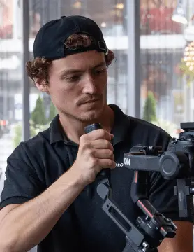 FX Productions Canada A man wearing a black cap and black shirt operates a professional camera stabilizer indoors, showcasing the expertise of FX Productions Canada, a leading Toronto Video Production company. Toronto Video Production Company