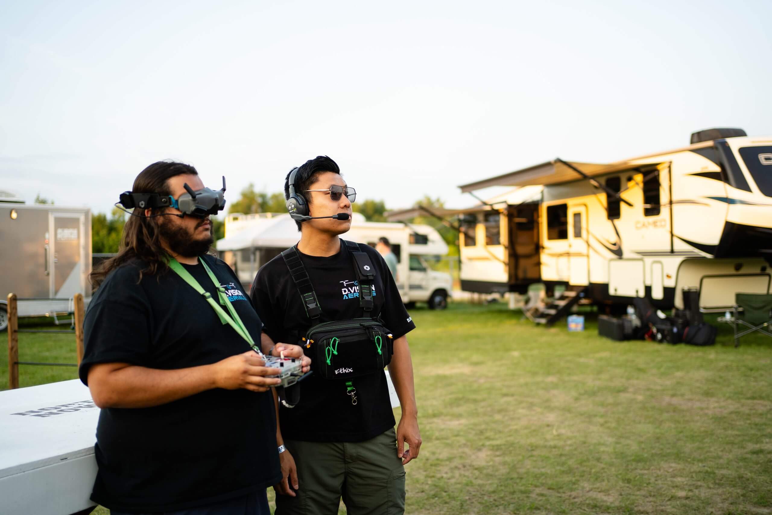 FX Productions Canada Two people operate a drone outdoors near several RVs; one wears FPV goggles and the other uses a headset and remote control, showcasing professional skills from FX Productions Canada, a leading video production company. Toronto Video Production Company
