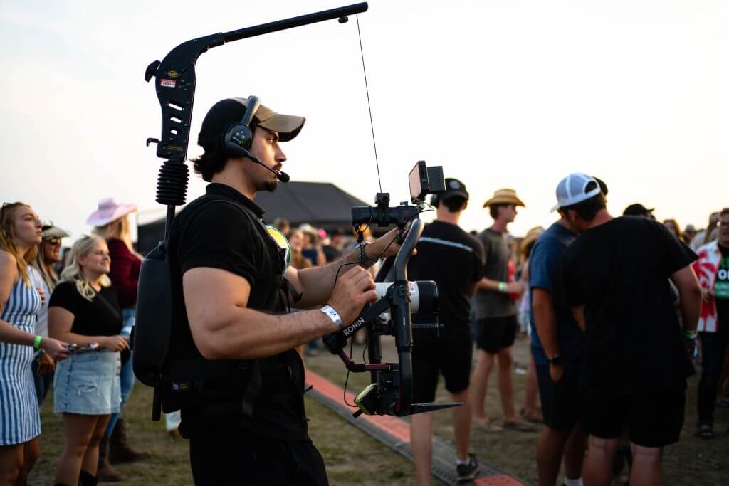 FX Productions Canada A camera operator with stabilizing gear films a crowd of people outdoors during an event, showcasing the expertise of Toronto Video Production professionals. Toronto Video Production Company
