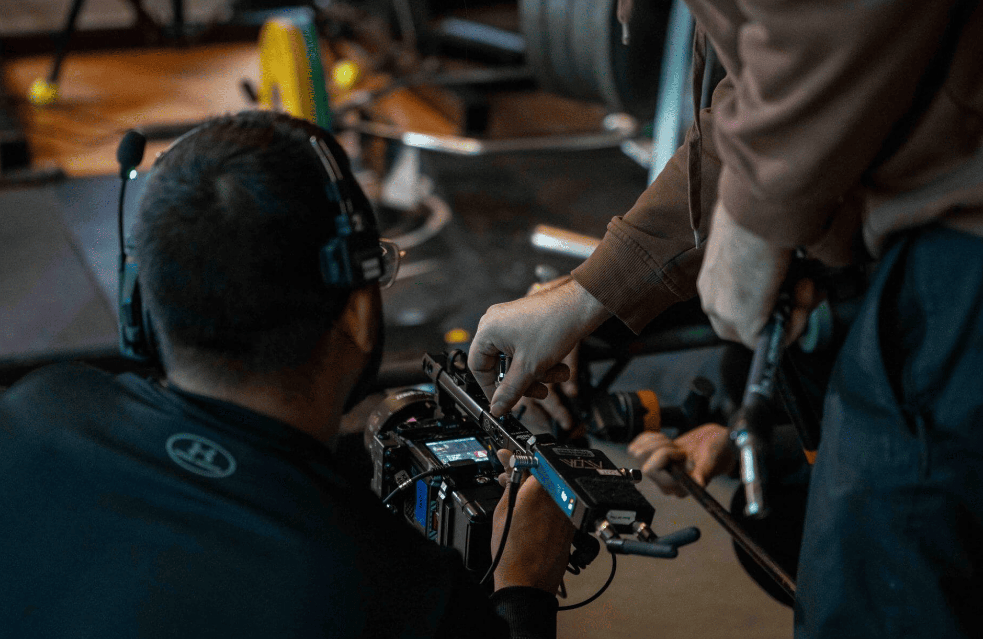 FX Productions Canada Two people adjust settings on a professional video camera in a studio, with one person wearing a headset and another holding tools, showcasing the expertise of FX Productions Canada, a leading Toronto Production Company. Toronto Video Production Company