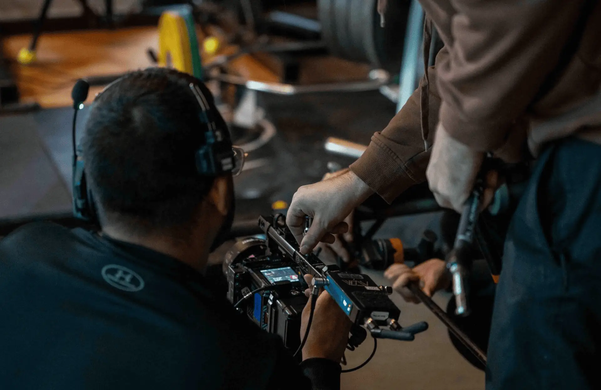 FX Productions Canada Two people adjust settings on a professional video camera in a studio, with one person wearing a headset and another holding tools, showcasing the expertise of FX Productions Canada, a leading Toronto Production Company. Toronto Video Production Company