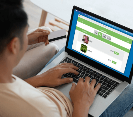 FX Productions Canada A person holds a credit card while shopping for vegetables online, browsing images and prices of mint and lettuce on their laptop. This scene is brought to life by Toronto Video Production experts. Toronto Video Production Company