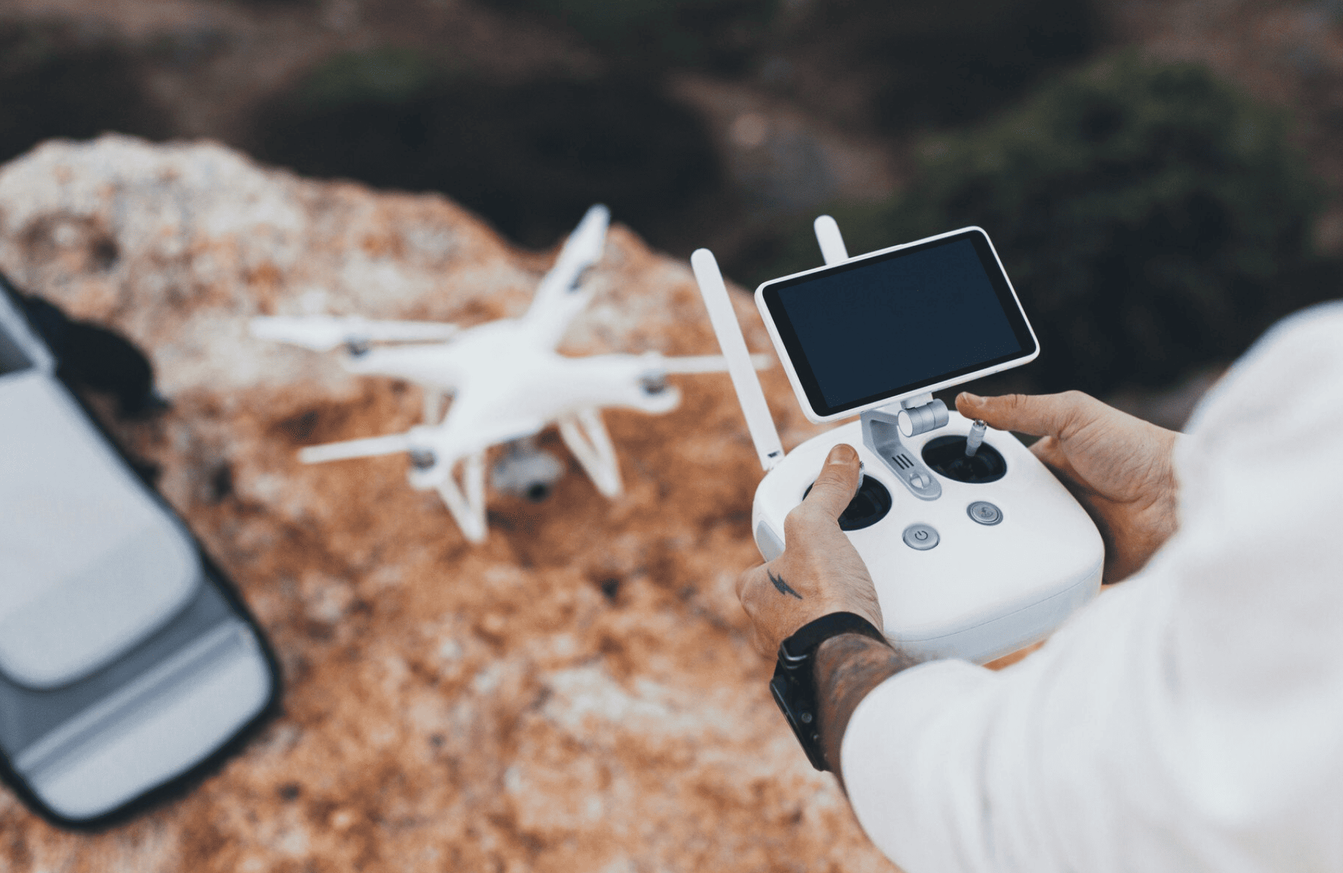 FX Productions Canada A person operates a white drone using a remote controller with a smartphone attached, standing outdoors on rocky terrain—a scene that could be captured by FX Productions Canada, a leading Toronto Production Company. Toronto Video Production Company