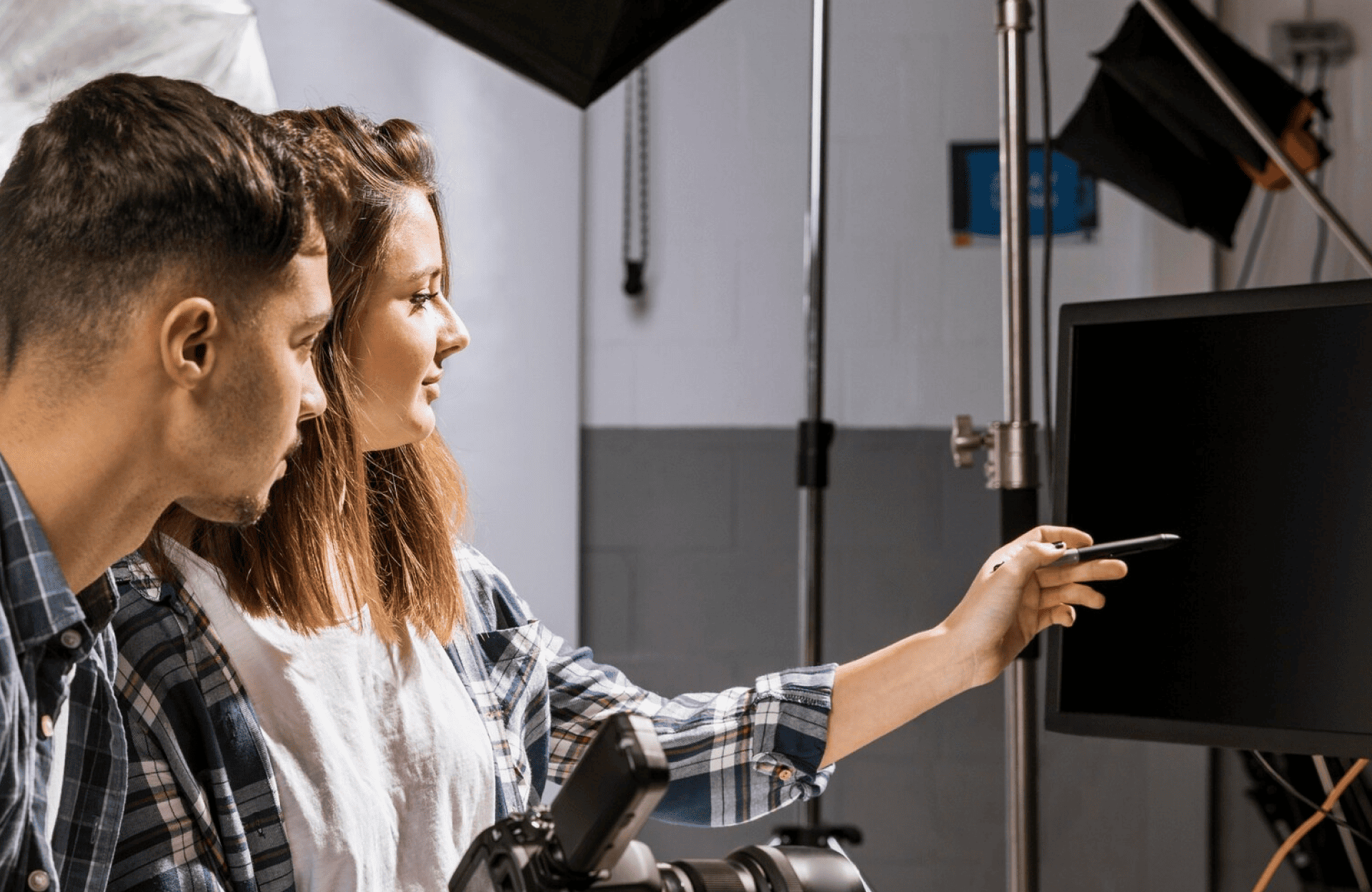 FX Productions Canada In a photography studio, two people from FX Productions Canada look at a blank computer monitor, with one person pointing at the screen using a pen. Toronto Video Production Company