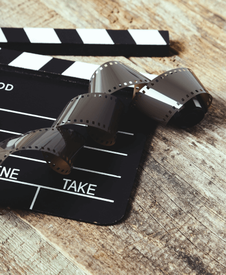 FX Productions Canada A close-up of a film clapperboard and a curled strip of photographic film on a wooden surface, capturing the creative spirit of Toronto Video Production. Toronto Video Production Company
