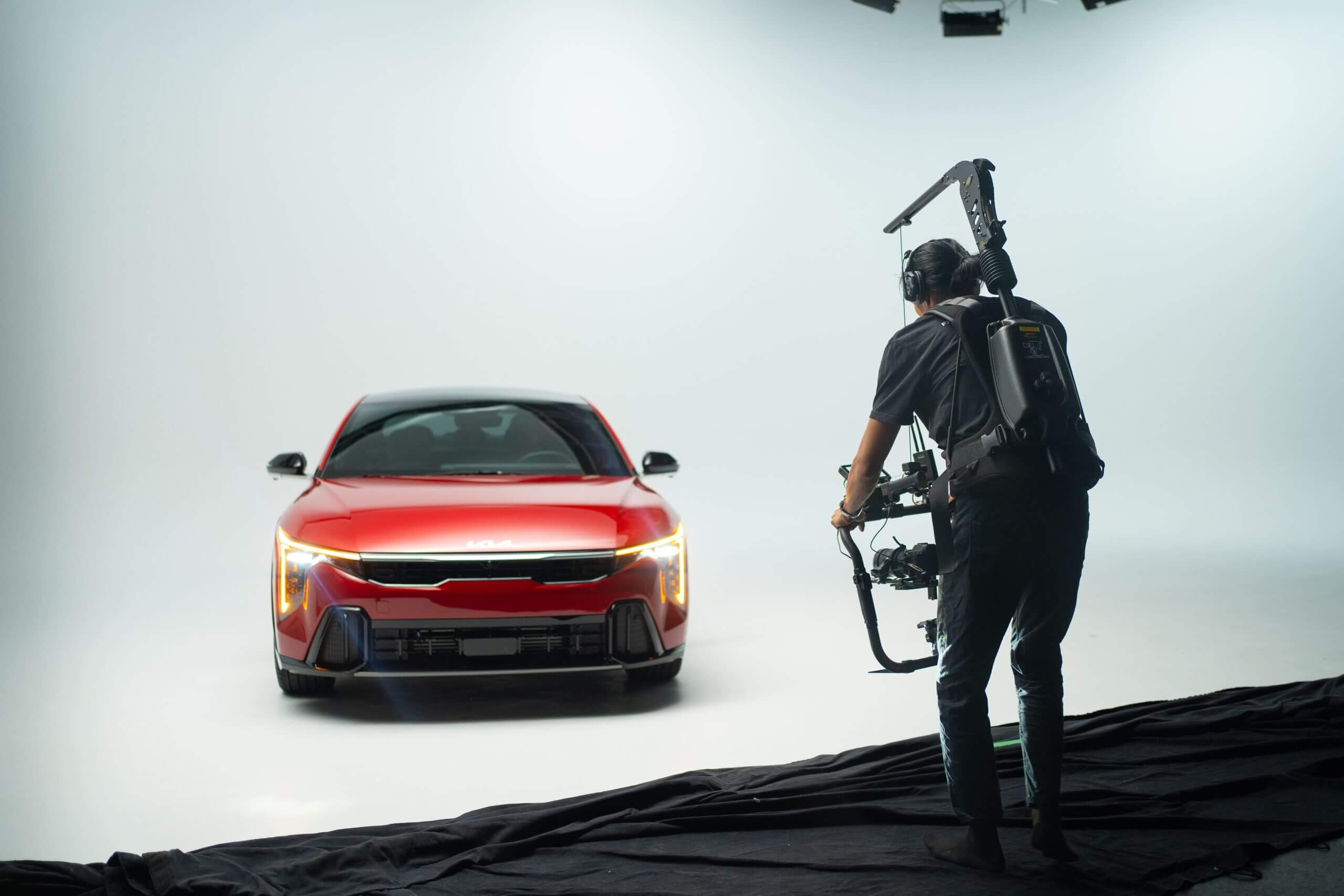 FX Productions Canada A videographer with a stabilizer films a red car in a professional studio with a plain white background for FX Productions Canada, a leading Toronto Video Production company. Toronto Video Production Company