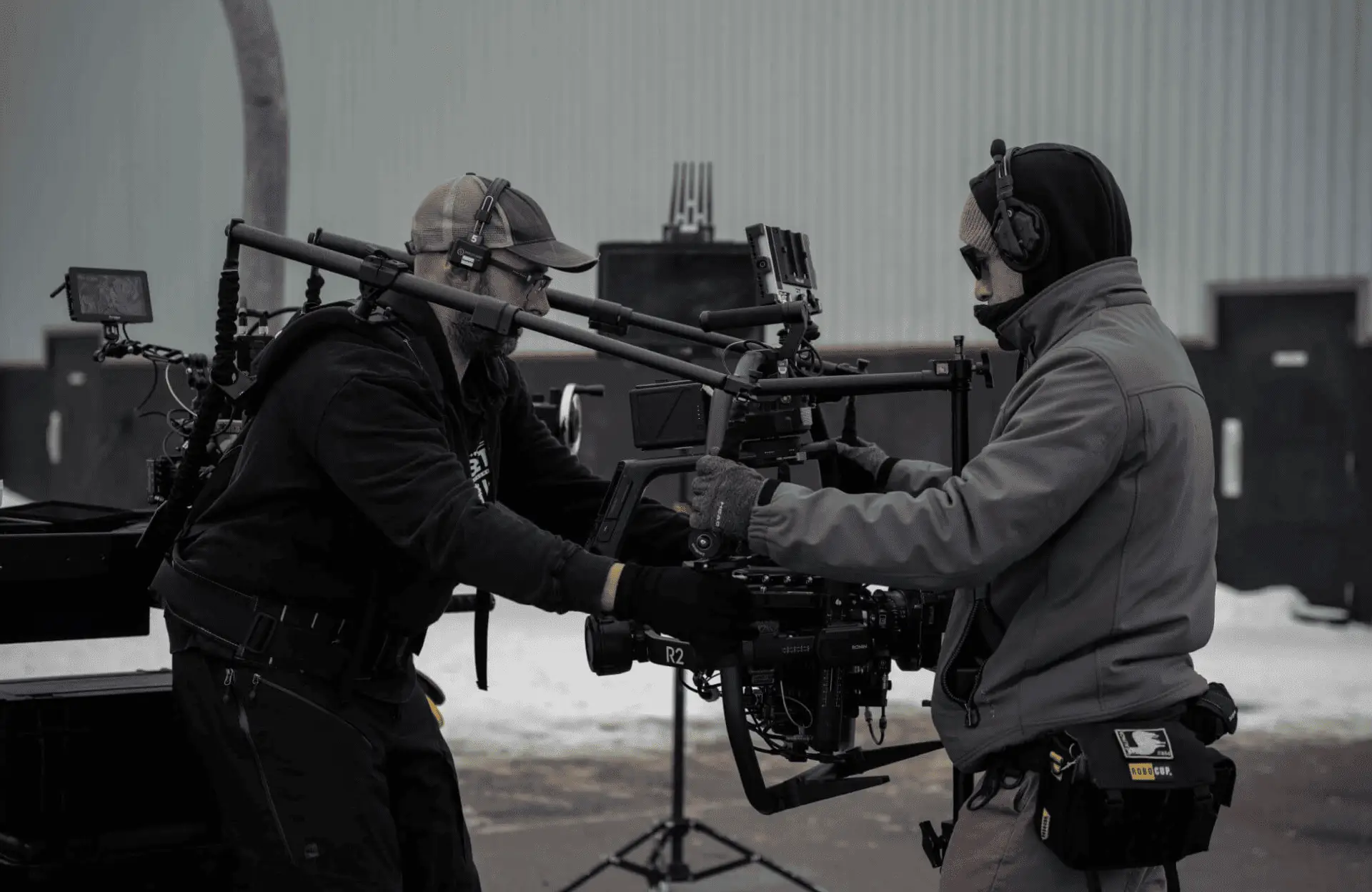 FX Productions Canada Two crew members from Toronto Production Company operate a mounted camera rig outdoors on a snowy film set, both wearing headsets and winter clothing. Snow blankets the ground in the background, capturing the essence of FX Productions Canada. Toronto Video Production Company