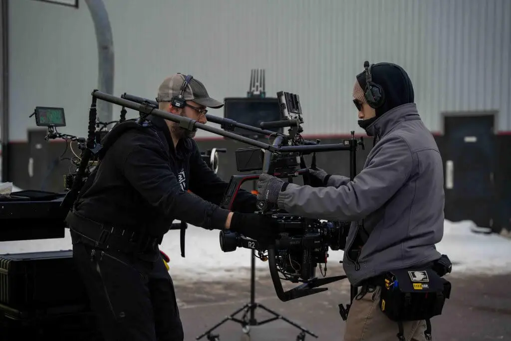 FX Productions Canada Two crew members from a Toronto Video Production team operate a professional camera rig outdoors, wearing headsets and winter clothing, with snow visible on the ground. Toronto Video Production Company